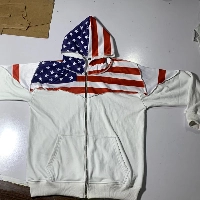  white zip-up hoodie featuring a bold American flag design across the chest, shoulders, and hood.
